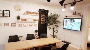 a dining room with a table and a tv on a wall at Hongdae Mainstreet Two Room House in Seoul