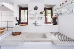 a white kitchen with a sink and some windows at Melia Cottage in Tsagarada