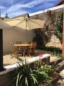 uma mesa e cadeiras com um guarda-sol num jardim em Appartements Le Cru Colbert em Beaune