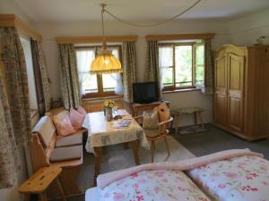 a living room with a bed and a table and a television at Pension Marianne - Chiemgau Karte in Inzell