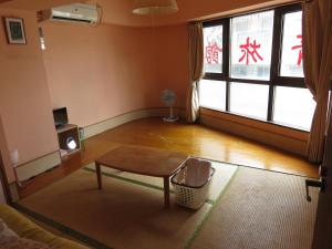 a living room with a table and a large window at Hostel Hakuseiso in Naha