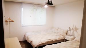 a bedroom with two beds and a window at Hongdae Mainstreet Two Room House in Seoul