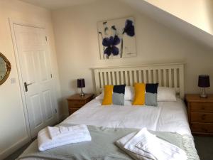 a bedroom with a white bed with yellow and blue pillows at Jubilee House in Oakham