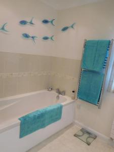 a bathroom with a tub and blue fish on the wall at Hysett House in Cocking