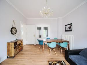 a living room with a dining room table and blue chairs at City Apartments Siegburg in Siegburg