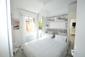 Dormitorio blanco con cama con sábanas y almohadas blancas en La villa Mauricia en Lacanau-Océan