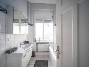 a white bathroom with a sink and a window at City Apartments Siegburg in Siegburg