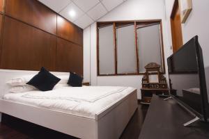 a bedroom with a bed and a flat screen tv at Narra House Sukhumvit58 in Bangkok