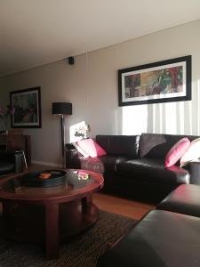 a living room with a leather couch and a table at A310 Lagoon Beach Apartment & Spa in Cape Town +15 photos