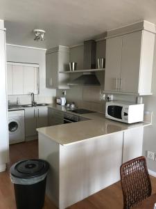 a white kitchen with a counter and a microwave at A310 Lagoon Beach Apartment & Spa in Cape Town