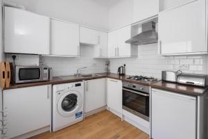 Una cocina con gabinetes blancos y lavadora y secadora. en Brighton Brunswick Apartments by MyHolidayLet, en Brighton & Hove 5 fotos más
