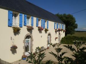 un edificio blanco con persianas azules y flores en él en La Cle Des Champs en Saint-Pabu