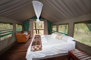 1 dormitorio en una tienda de campaña con 1 cama y 1 silla en Ndzhaka Tented Camp, en Manyeleti Game Reserve