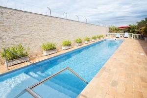 una piscina junto a una pared de ladrillo con plantas en 50+ Hotel Flat, en São José do Rio Preto
