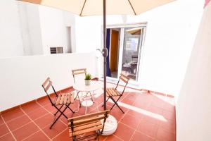 um pátio com uma mesa, cadeiras e um guarda-sol em Malaga City Suites Barceló 30 em Málaga