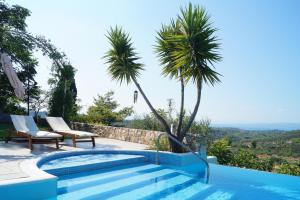 a swimming pool with two chairs and two palm trees at Villa Marrone Splendid Seaview in Markópoulon Oropoú