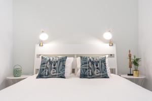 - une chambre avec un lit blanc et des oreillers bleus dans l'établissement Slowlife Furadouro, à Furadouro