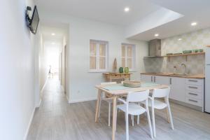eine Küche mit einem Tisch und weißen Stühlen in der Unterkunft Slowlife Furadouro in Furadouro + 13 Fotos