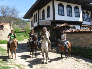 a group of people riding horses in front of a building at Sava Cupetsa Guest House in Zheravna