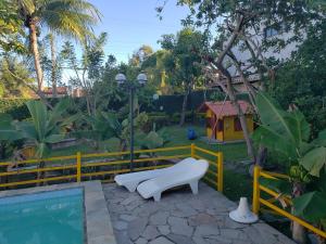 a pool with a white bench next to a yellow fence at Itaparica - Vera Cruz 12 pessoas in Vera Cruz de Itaparica