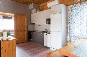 cocina con electrodomésticos blancos y pared de madera en Leenan tupa, en Sonka