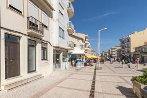 eine Straße in einer Stadt mit Gebäuden und Passanten in der Unterkunft Slowlife Furadouro in Furadouro