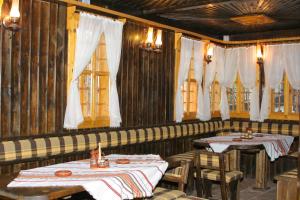 a restaurant with two tables and chairs and windows at Sava Cupetsa Guest House in Zheravna