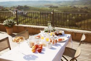 a white table with food and drinks on a balcony at Klinec Plešivo Art Rooms in Dobrovo