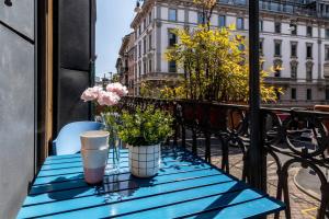 a blue table with flowers on a balcony at JOIVY Charming Apt with Terrace in the very heart of Milan in Milan