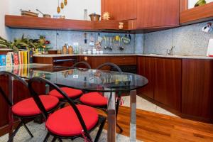 a glass table with red chairs in a kitchen at JOIVY Charming Apt with Terrace in the very heart of Milan in Milan