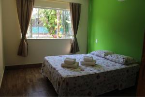 a bedroom with a bed with green walls and a window at PachaMama Flats - Taipu de Fora in Barra Grande