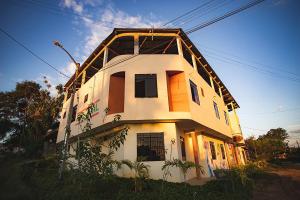 a large white house with a gambrel roof at El Mural Backpackers in Tarapoto