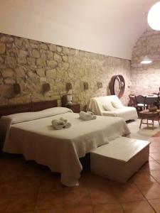 1 dormitorio con 2 camas y pared de piedra en Liolà, en Módica