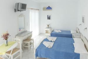 1 dormitorio con 2 camas, TV y sofá en Moschoula Studios en Parikia