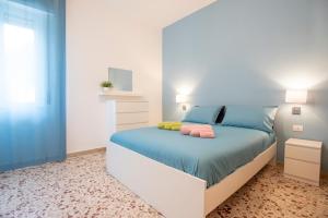 1 dormitorio con 1 cama con sábanas azules y almohadas rosas en DELPOSTO Marina di Ragusa (lp) en Marina di Ragusa
