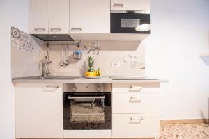 a kitchen with white cabinets and a sink at DELPOSTO Marina di Ragusa (lp) in Marina di Ragusa +11 photos