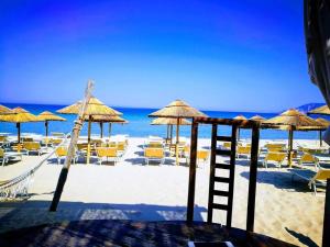 a beach with chairs and umbrellas and the ocean at Sa domu rubia in Iglesias
