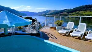 a swimming pool with chairs and a view of a lake at Hotel Villa das Termas in Marcelino Ramos