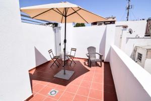 un patio con mesa, sillas y sombrilla en Malaga City Suites Barceló 30, en Málaga