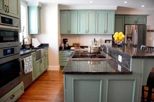 a kitchen with green cabinets and a stove top oven at Sally Webster Inn in Rockport