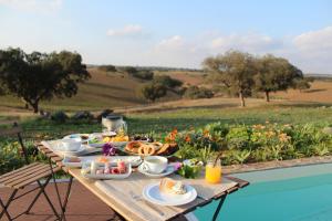 uma mesa de piquenique com comida para o pequeno-almoço ao lado de uma piscina em Agroturismo Xistos em Cerca