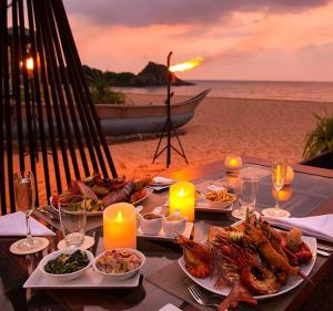 a table with plates of food and candles on the beach at Ocean View in Bentota