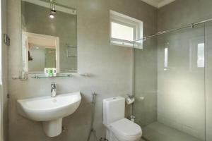W łazience znajduje się umywalka, toaleta i lustro. w obiekcie Ocean View w mieście Bentota