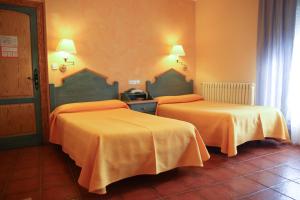 2 camas en una habitación de hotel con sábanas de color naranja en Hotel Fray Tomás, en Berlanga de Duero
