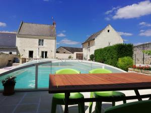 una mesa y sillas junto a una piscina en La Bonne Note, en Chinon