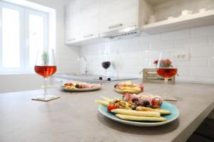 two glasses of wine and plates of food on a kitchen counter at Saint Simeon room and apartment in Zadar