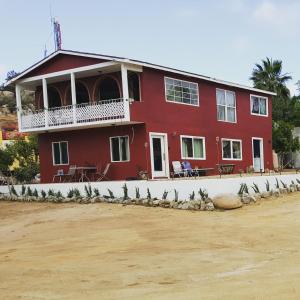 Une maison rouge avec un groupe d'oiseaux devant elle dans l'établissement Villa De Coral, à Valle de Guadalupe