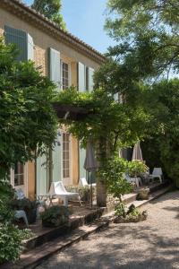 a building with chairs and umbrellas in a yard at Logis Hôtel Castel Mouisson in Barbentane