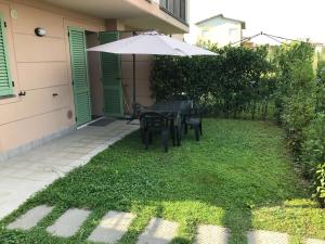 un patio con mesa, sillas y sombrilla en Appartamento "Corte Ceci" en Lucca