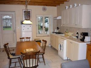 Saint-Étienne-de-Tulmont的住宿－拉佩納迭熱度假屋，一个带桌子的厨房和一个带洗衣机的厨房
